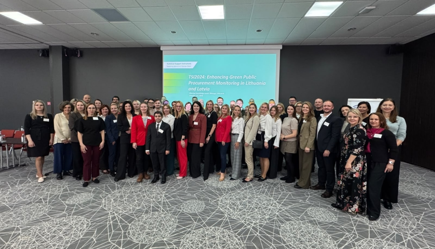 Cilvēku grupa, projektors ar prezentāciju, telpa, apgaismojums, paklājs