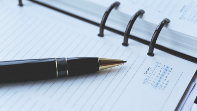 Pildspalva novietota uz plānotāja, norādot uz kalendāru