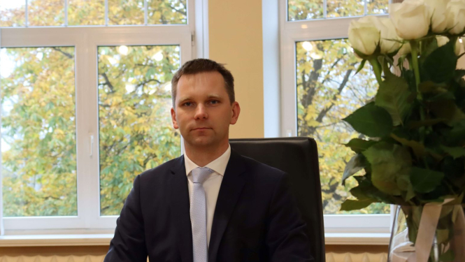 Iepirkumu uzraudzības biroja vadītājs Artis Lapiņš sēž kabinetā pie galda 