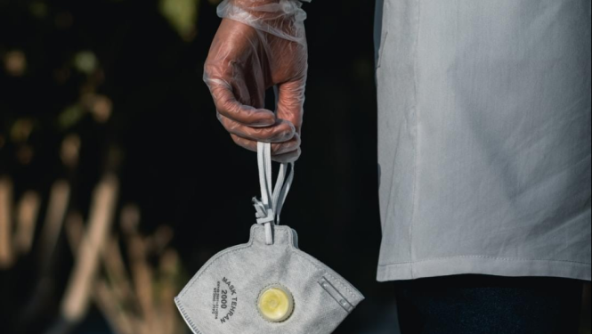 Ārsts tur mutes un deguna dobuma aizsegu (sejas masku)