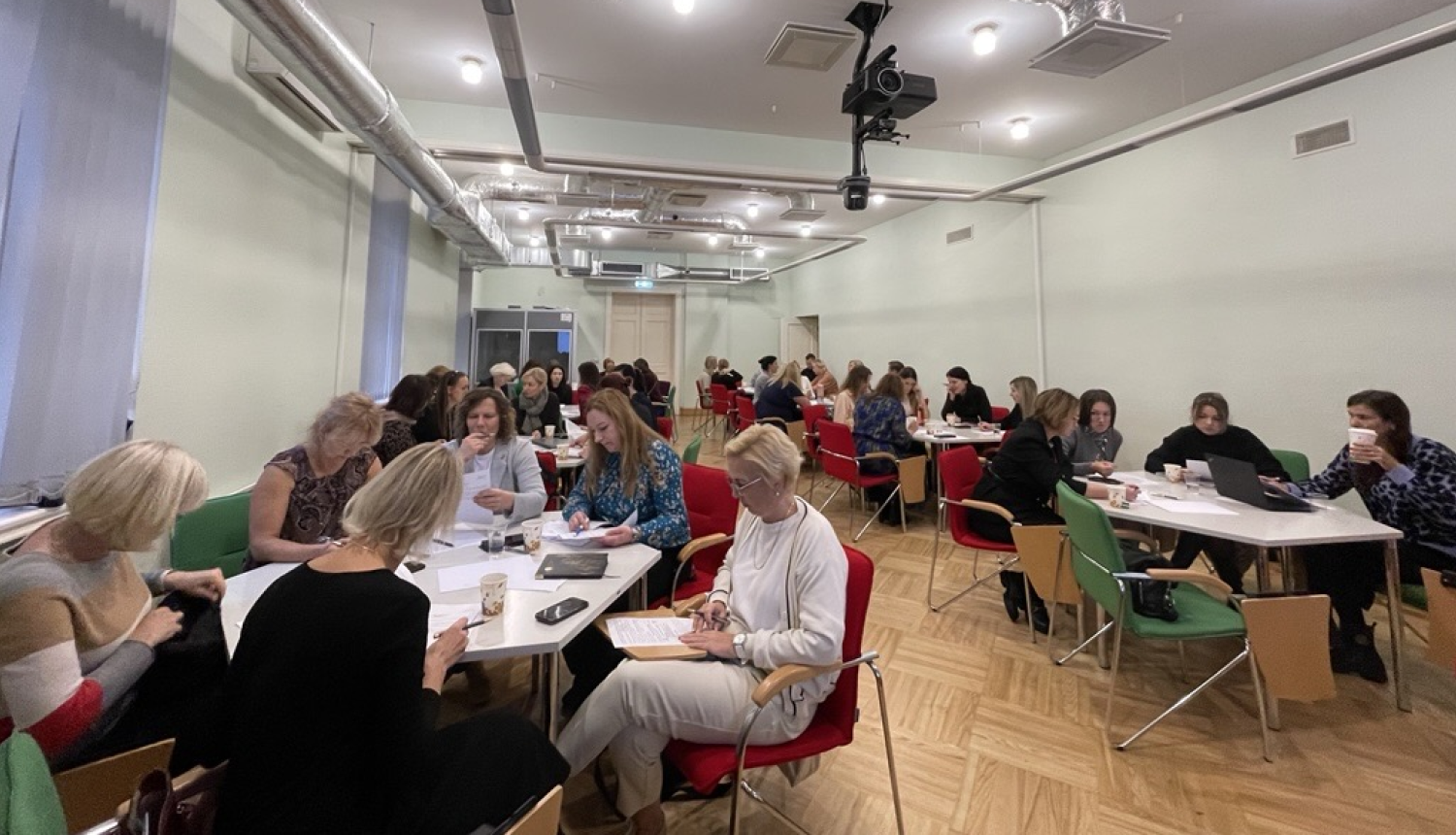 Seminārs ES fondiem, dalībnieki, galdi, krēsli, uz galdiem darba lapas