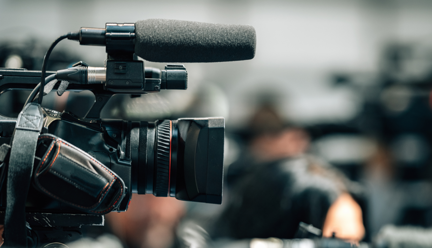 Operatoru profesionālā videokamera ar mikrofonu (redzama no sānskata)